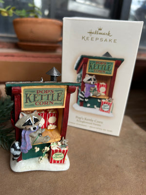 Decorative Pop the Raccoon sitting at his popcorn stand 'Pops Kettle Corn'  holiday ornament