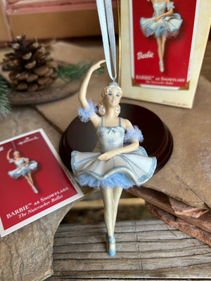 A Hallmark Keepsake ornament featuring Barbie as a ballerina in a blue tutu, striking a pose, with a 'The Nutcracker Ballet' theme. The ornament is displayed in front of its packaging.