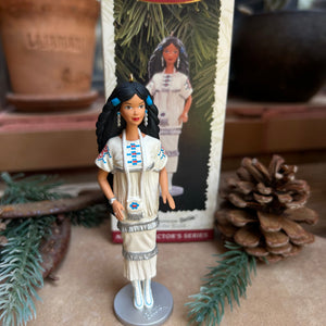 Action figure on a stand with a display card featuring a Native American woman, surrounded by decorative elements.
