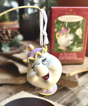 Decorative ornament of a character from a movie, hanging on a string with a box in the background.