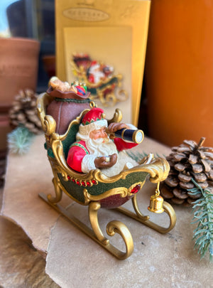 Santa in his sleigh using his telescope to plot the course of his busy evening ahead delivering gifts to all the children in the world. a beautiful detailed colorful ornament or collectible