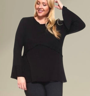 Woman wearing a black top with a layered design on a beige background